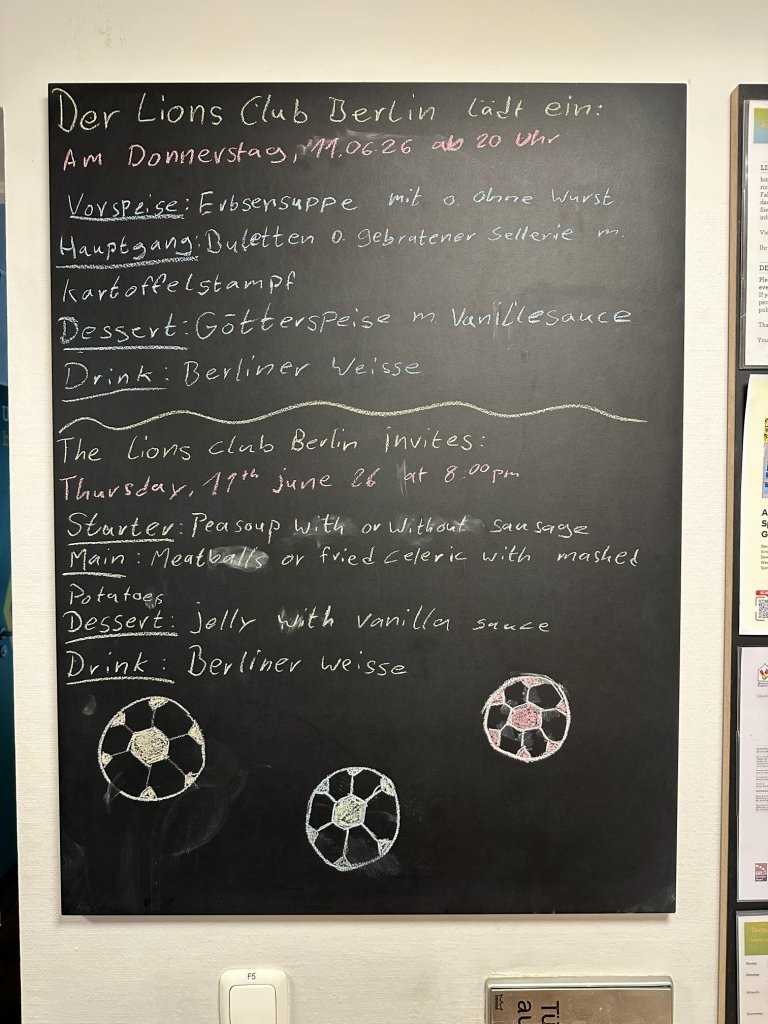 Eine beschriebene Kreidetafel mit Menüangaben in deutscher und englischer Sprache.