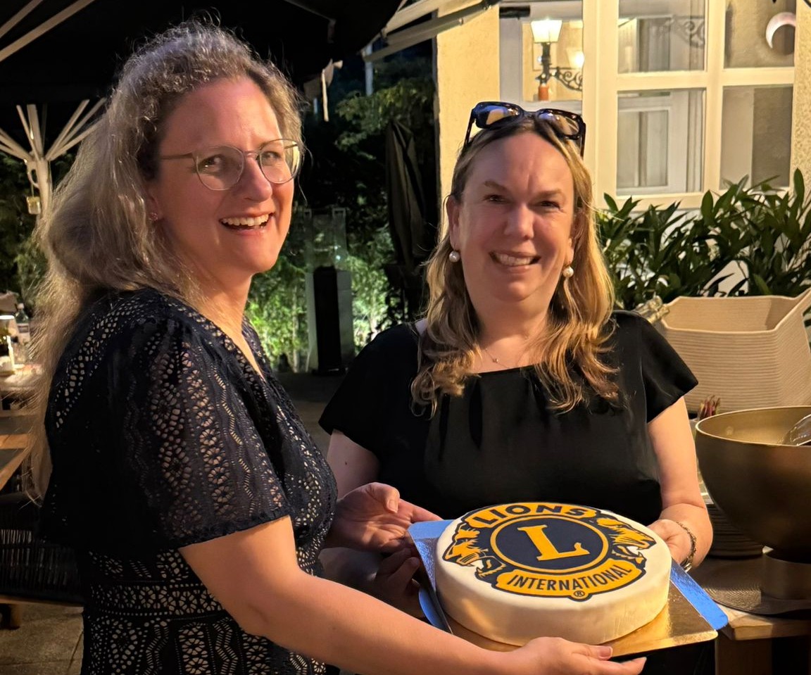 Zwei Frauen präsentieren eine Torte mit Lions-Loge