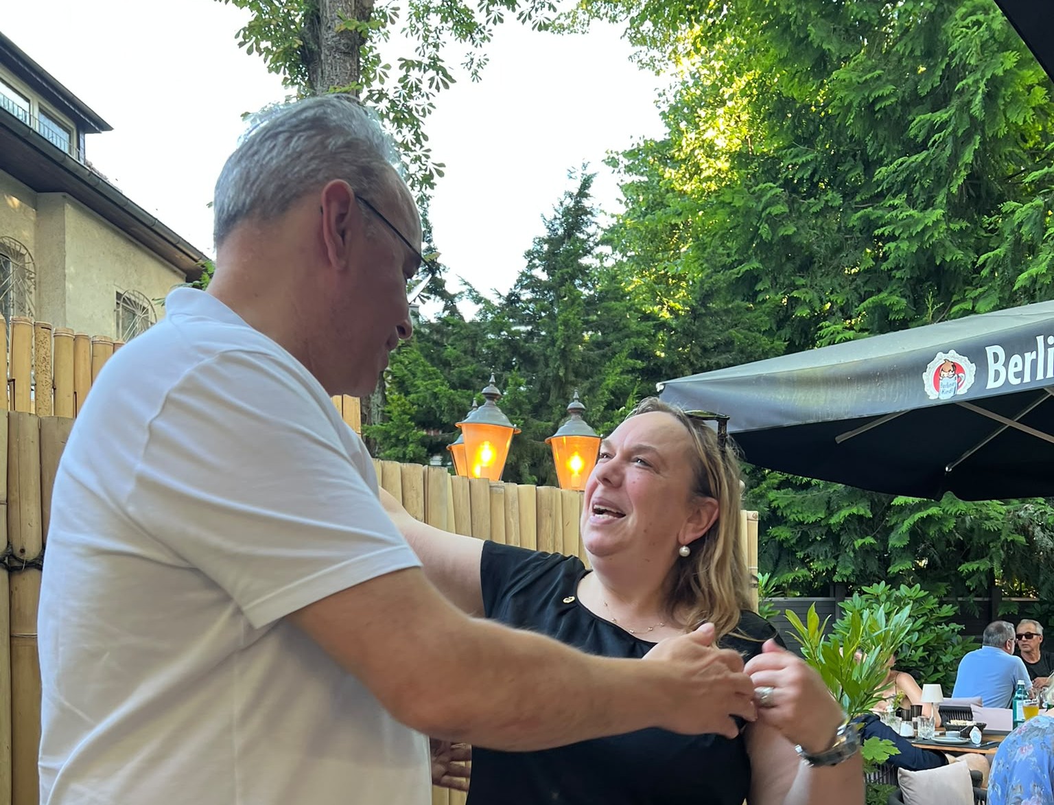 Zwei Personen stehen sich gegenüber, während eine Person der anderen ein Abzeichen ansteckt.