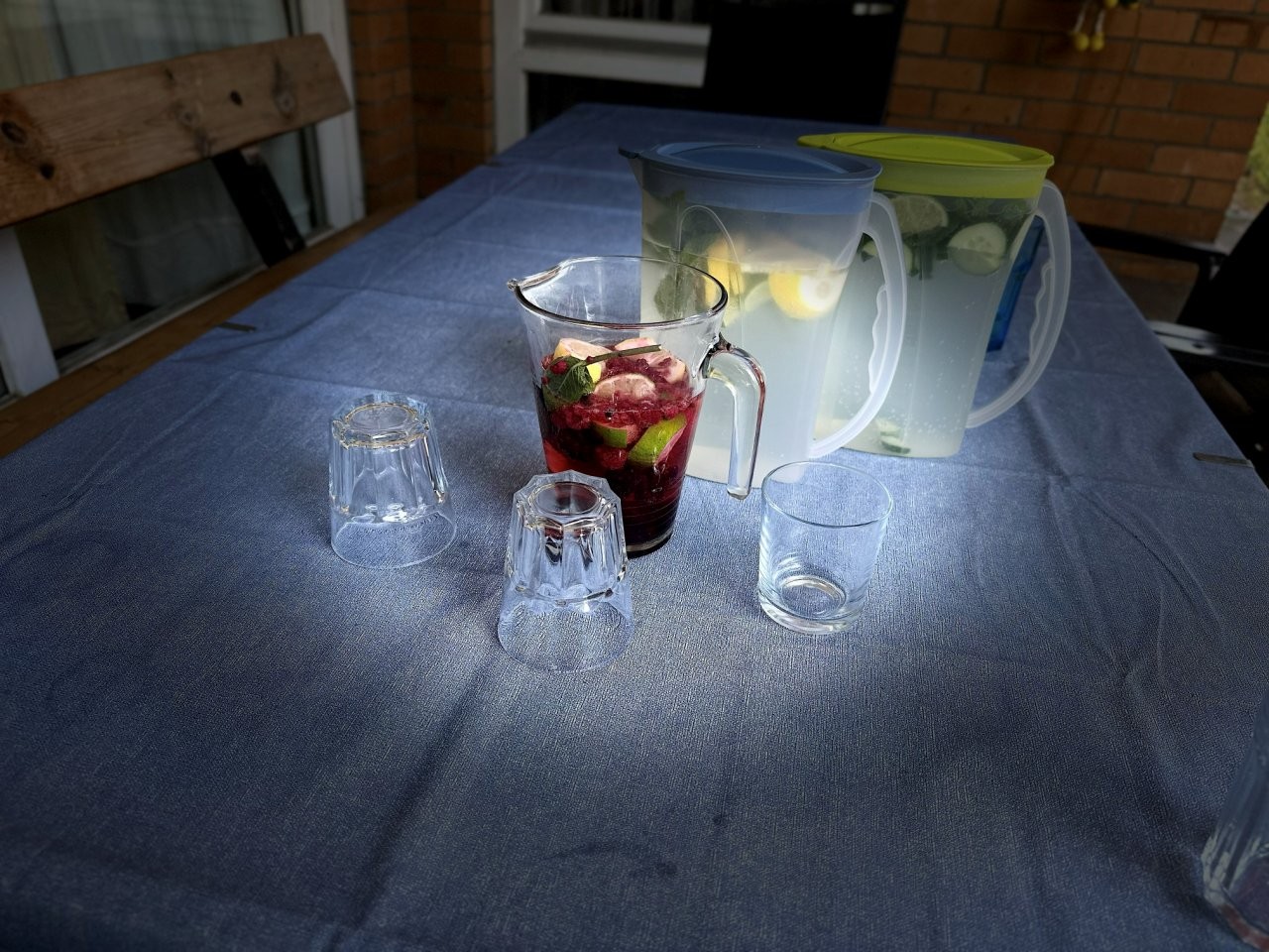 Mehrere Getränkekrüge und Gläser stehen auf einem Tisch im Freien.