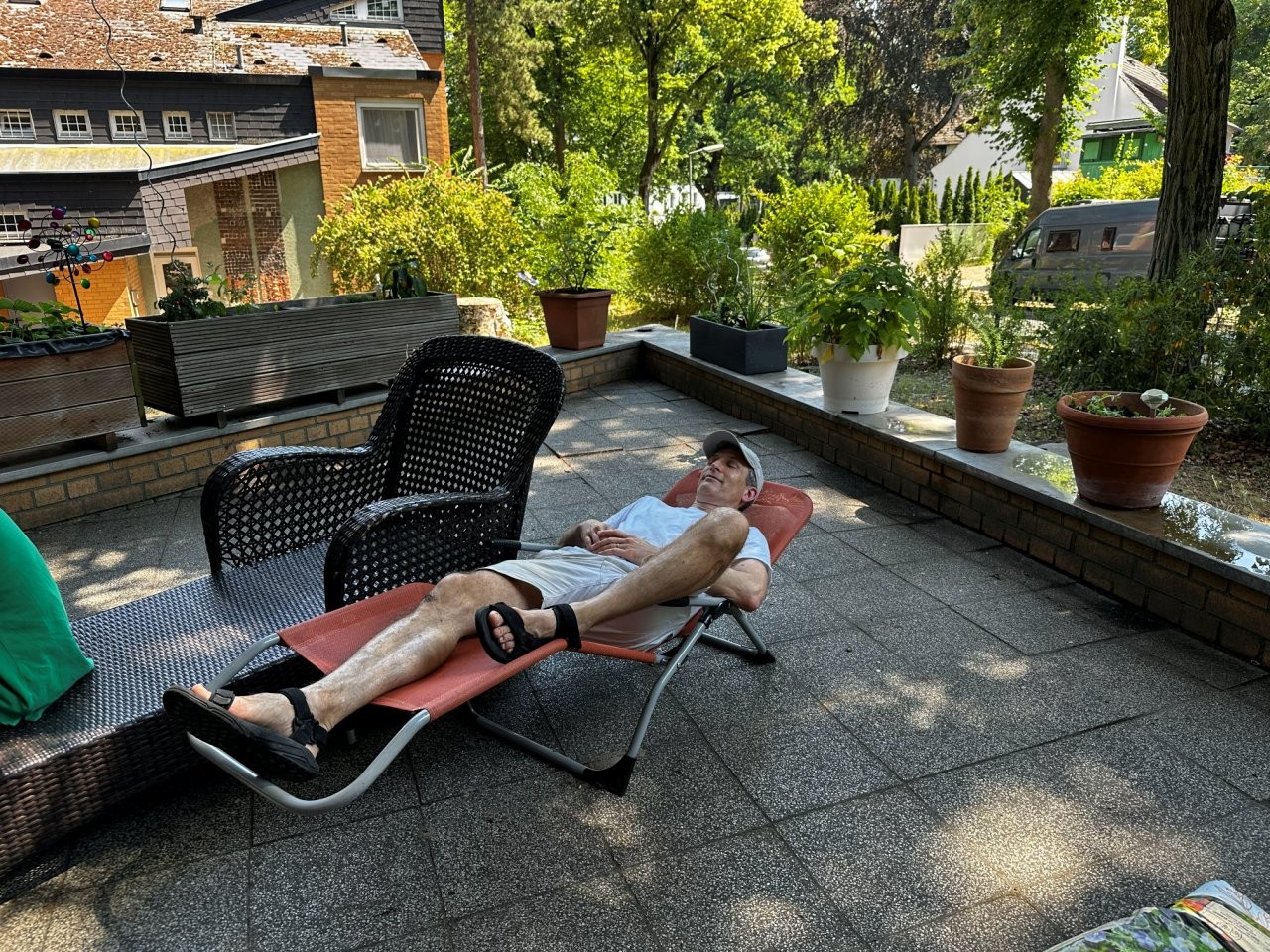 Ein Mann liegt auf einem Liegestuhl im Schatten auf einer Terrasse